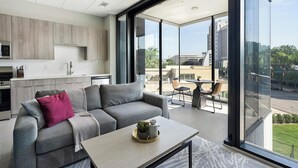 Un espacio habitable moderno con un sofá gris, una mesa de centro y vistas de la ciudad a través de grandes ventanales.