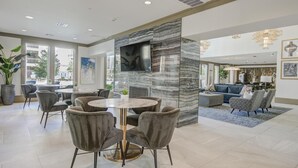 Un hall d’hôtel moderne avec un mur en marbre, une table de salle à manger ronde et des sièges confortables.