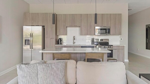 Una cocina moderna con una isla central, electrodomésticos de acero inoxidable y armarios de madera clara.