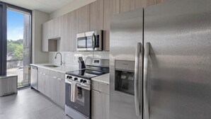 A modern kitchen with stainless steel appliances, a built-in oven, microwave, and refrigerator. - Landing | Spectacular 1BD in Fountain Heights (Birmingham)