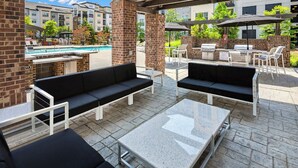 An outdoor patio with black cushioned seating, a granite table, and a barbecue grill. - Landing | Stylish 2BD, Game Room, Gym (Charlotte)