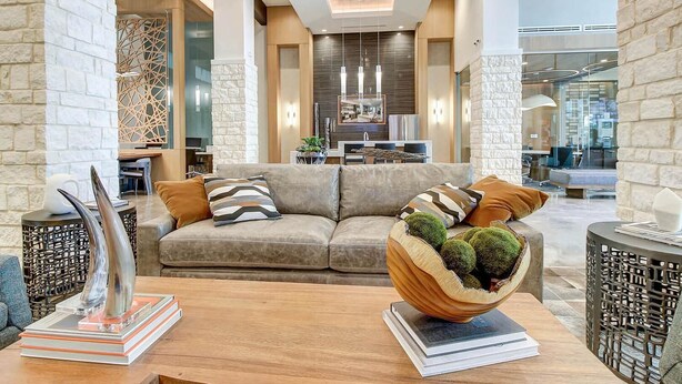 A modern living room with a sofa, decorative pillows, a wooden coffee table, and a unique spherical plant holder. - Landing | Beautiful 1BD, Game Room, Clubhouse (San Antonio)