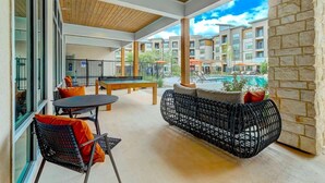 A balcony with a pool view, outdoor seating, and a table. - Landing | Beautiful 1BD, Game Room, Clubhouse (San Antonio)