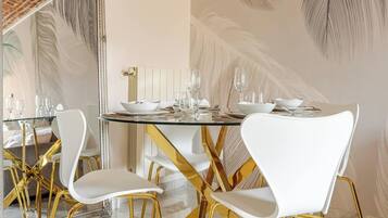 Un comedor con una mesa redonda, sillas blancas y patas doradas.