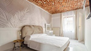 A bedroom with a brick ceiling, a bed with white linens, a small bedside table with a lamp, and a radiator.