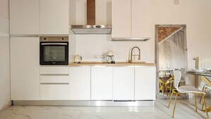 A modern kitchen with white cabinetry, a stainless steel oven, and a marble floor.
