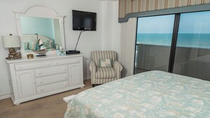 A bedroom with a bed, a dresser, a television, and a chair. - Water's Edge Retreat-Direct Oceanfront @ Sandpoint, 2BR Oceanfront Pool (Daytona Beach)