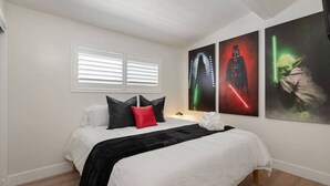 Un dormitorio con cama, almohadas, una colcha y tres carteles en la pared.