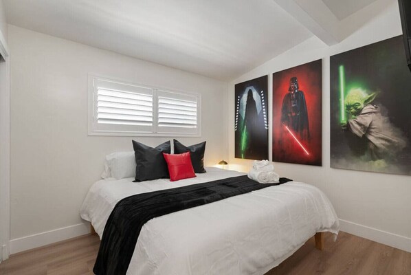 Un dormitorio con cama, almohadas, una colcha y tres carteles en la pared.