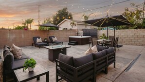 Un espacio de patio al aire libre con un sofá, sillas, una mesa y un jacuzzi.