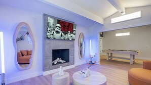 Una sala de estar moderna con chimenea, mesa de billar y sofá.