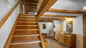 A wooden staircase leading to a room with a tiled floor, a wooden cabinet, and a chair.