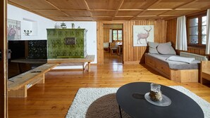 A cozy cabin interior with a wooden ceiling, a green cabinet, a sofa, and a dining area.