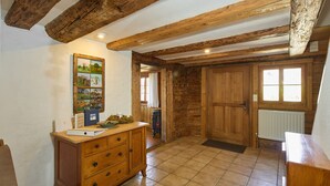 A rustic wooden room with a wooden cabinet, a tiled floor, and a large wooden door.