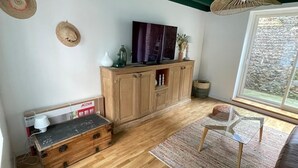 A living room with wooden flooring, a sofa, a coffee table, and a TV on a wooden cabinet.