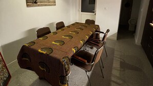 A dining area with a long table, chairs, pendant lights, and a poster on the wall.