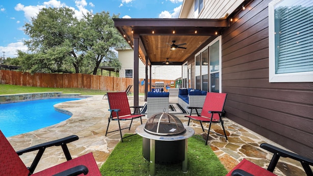 A covered patio area with a stone pool, outdoor furniture, and a fire pit. - Spacious 5BR Retreat with Heated Pool & Outdoor Games (San Antonio)