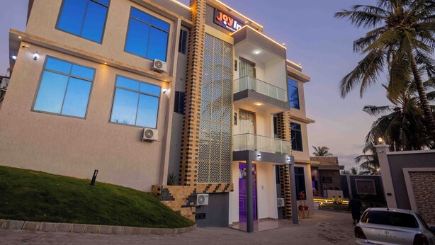 A modern hotel with a prominent sign, multiple balconies, and a well-maintained lawn.