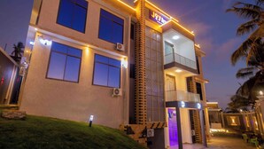 A modern hotel with a two-story structure, large windows, and a prominent entrance with a balcony.