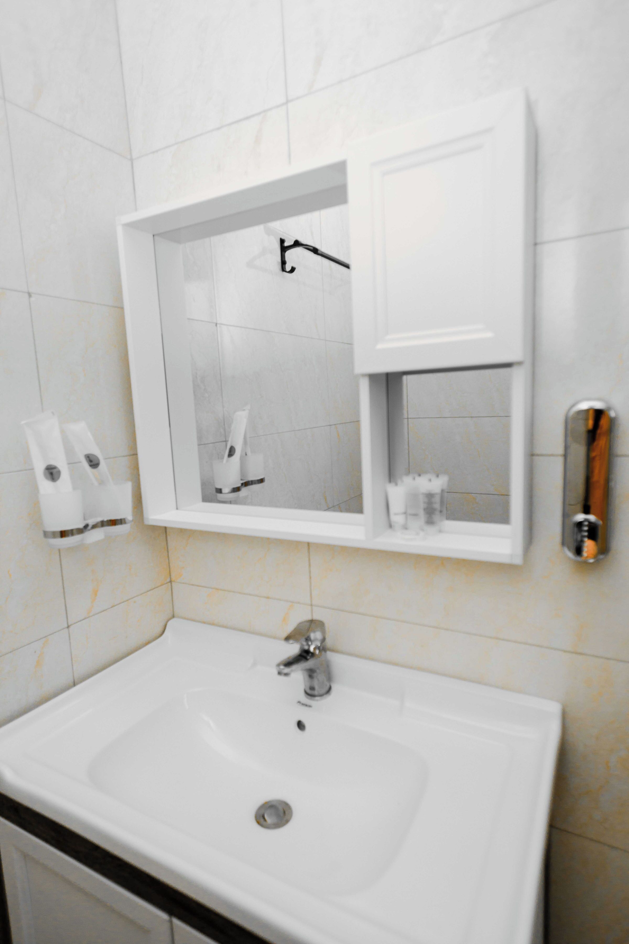A bathroom with a white sink, a mirror, and a towel dispenser.