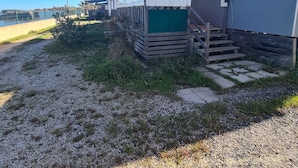 A single-story mobile home with a covered porch, a small set of stairs, and a fenced outdoor area.