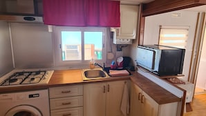A compact kitchen with a gas stove, a washing machine, and a microwave.