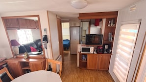 A compact living space with a dining area, kitchenette, and a small bedroom.