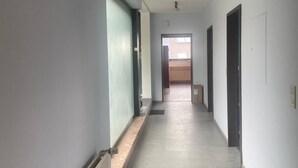 A long, narrow hallway with light-colored walls and a tiled floor. There are doors on both sides and a window at the end of the hallway. - Beautiful, large penthouse for a maximum of 4 people. Kitchen including all utensils (Wadgassen)