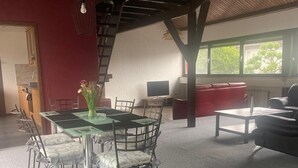 A dining area with a glass table and chairs, a red sofa, and a TV. - Beautiful, large penthouse for a maximum of 4 people. Kitchen including all utensils (Wadgassen)