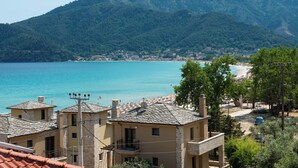 Un pueblo costero con edificios que dan a una playa y montañas al fondo.