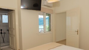 Un dormitorio con cama, ventana con vistas a montañas, puerta y unidad de aire acondicionado.