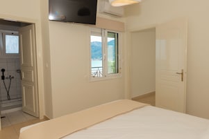 Un dormitorio con cama, ventana con vistas a montañas, puerta y unidad de aire acondicionado.