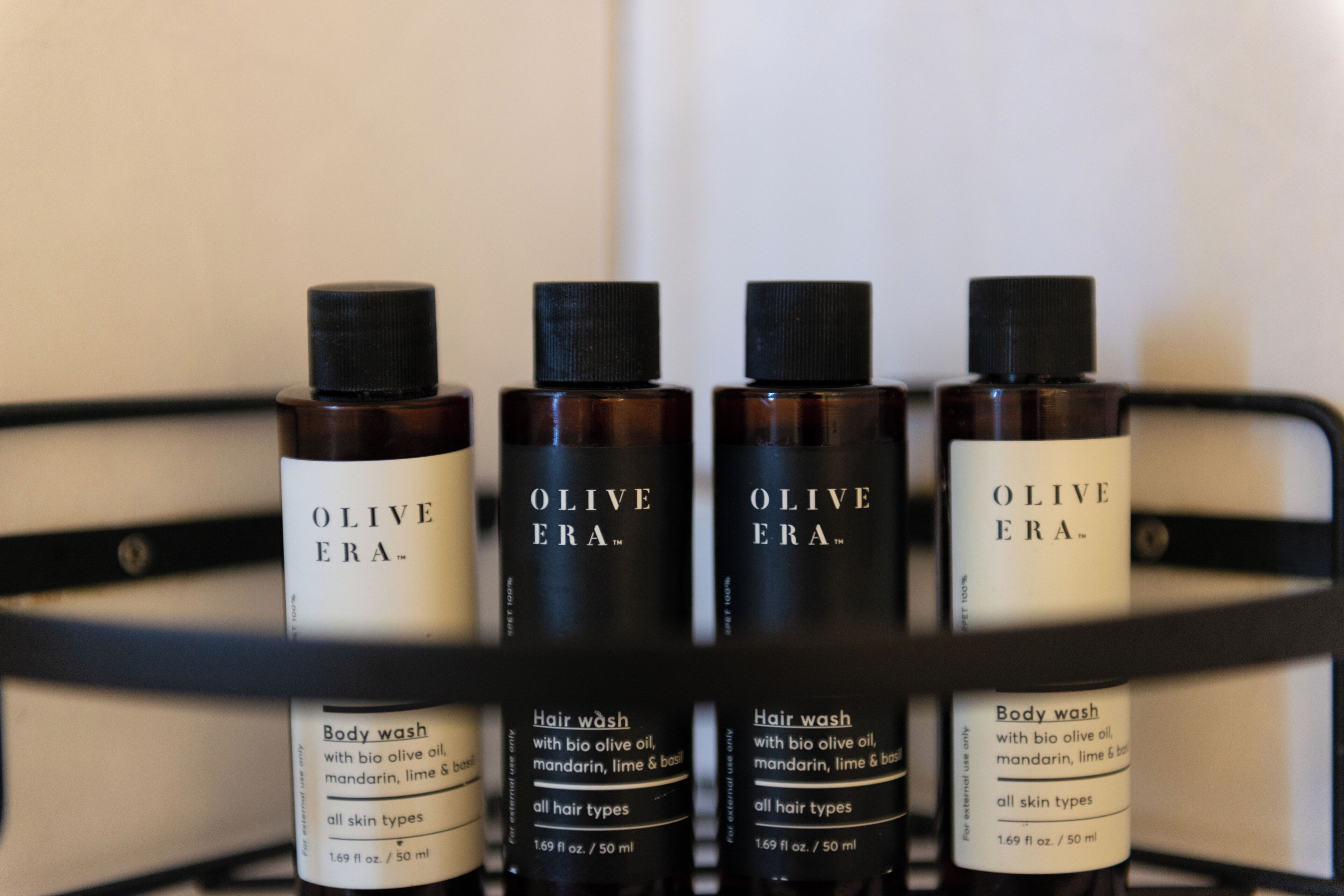 Four bottles of Olive Era body wash and hair wash on a shelf.