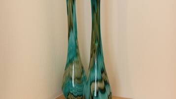 Two glass vases on a wooden shelf against a plain wall.