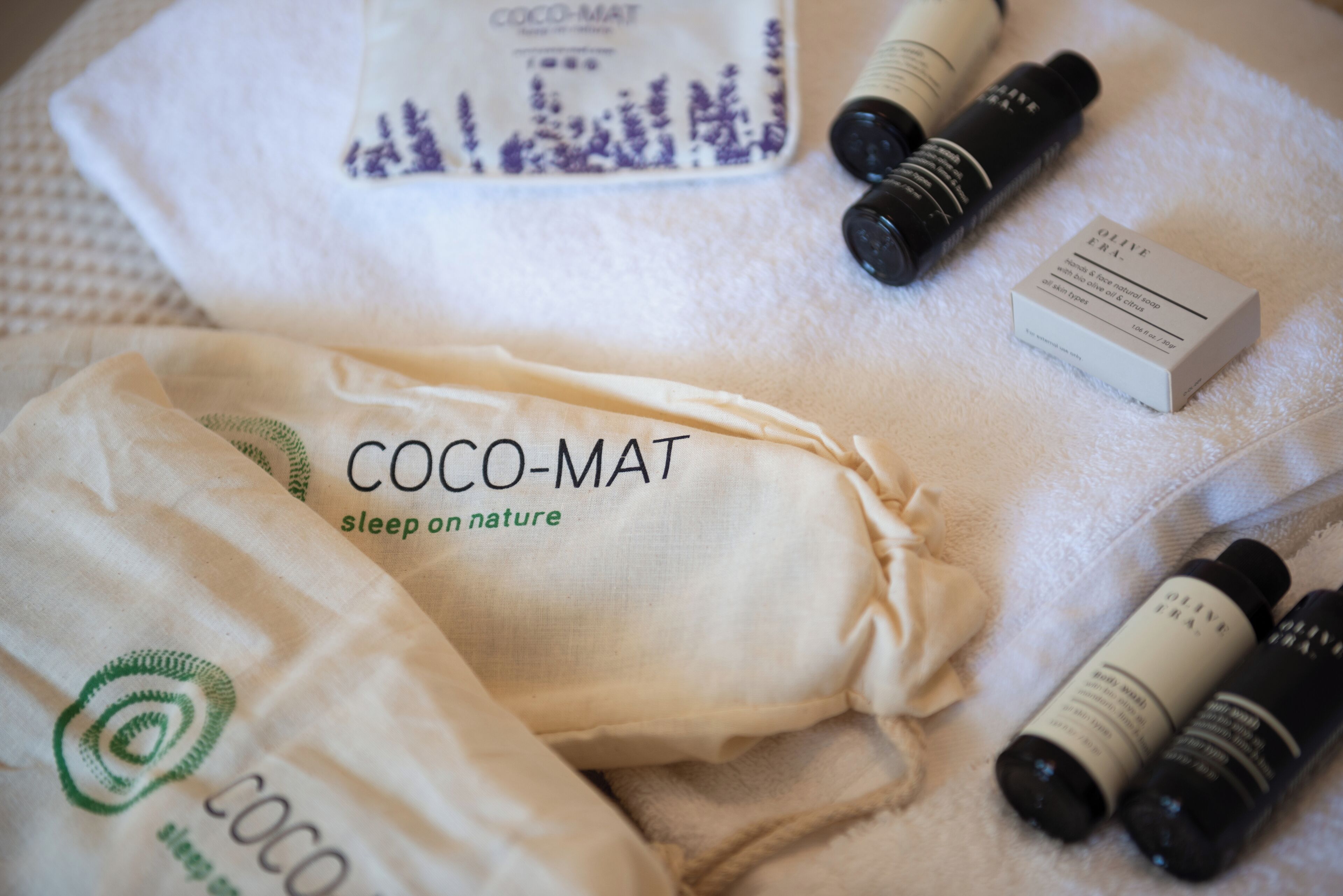 Un lit avec une couverture blanche et un oreiller sur lequel est inscrit : « COCO-MAT, dormez en harmonie avec la nature ».