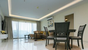 A modern living room with a dining area, featuring a sofa, chairs, a coffee table, and a TV.