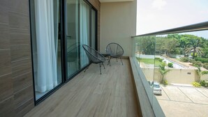 A balcony with a view of a residential area, two chairs, and a table.