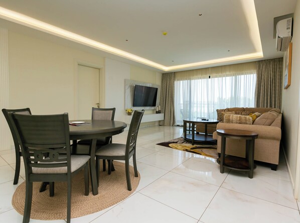 A modern living room with a dining area, a sofa, and a TV. - 2-bedroom apartment in amazing Accra with WiFi, fitness room, AC (Accra)