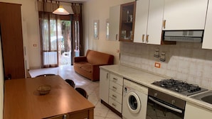 Uma cozinha compacta com máquina de lavar, fogão e área de refeições com mesa e cadeiras.