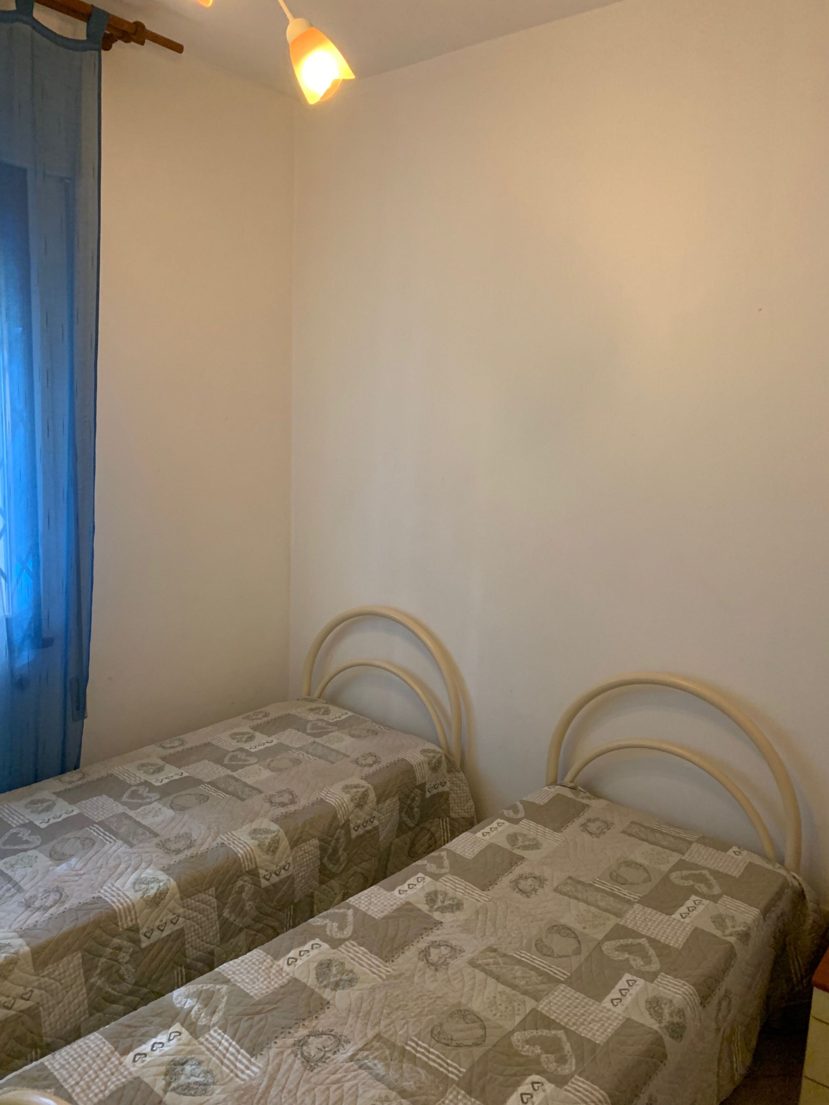 A room with two single beds, each with a patterned bedspread and headboard.