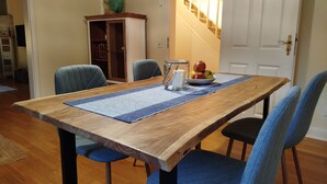A dining table with a blue placemat, surrounded by blue upholstered chairs. A bowl of fruit and a candle are on the table. - Villa Scharbeutz Pönitz, spacious, quiet, central (Scharbeutz)