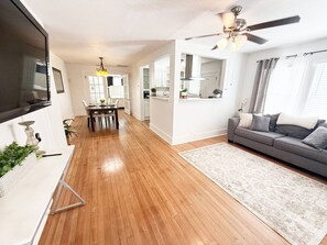 Un salon moderne avec un canapé gris, un plancher en bois et un ventilateur de plafond.
