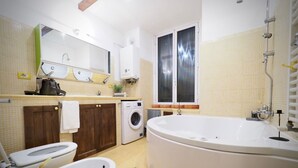 A modern bathroom with a large bathtub, a washing machine, a toilet, and a sink. - Dimora delle Camelie (Aquarium) genovabnb it (GENOVA)