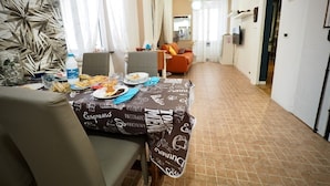 A dining area with a table set for two, a sofa, and a kitchen in the background. - Dimora delle Camelie (Aquarium) genovabnb it (GENOVA)
