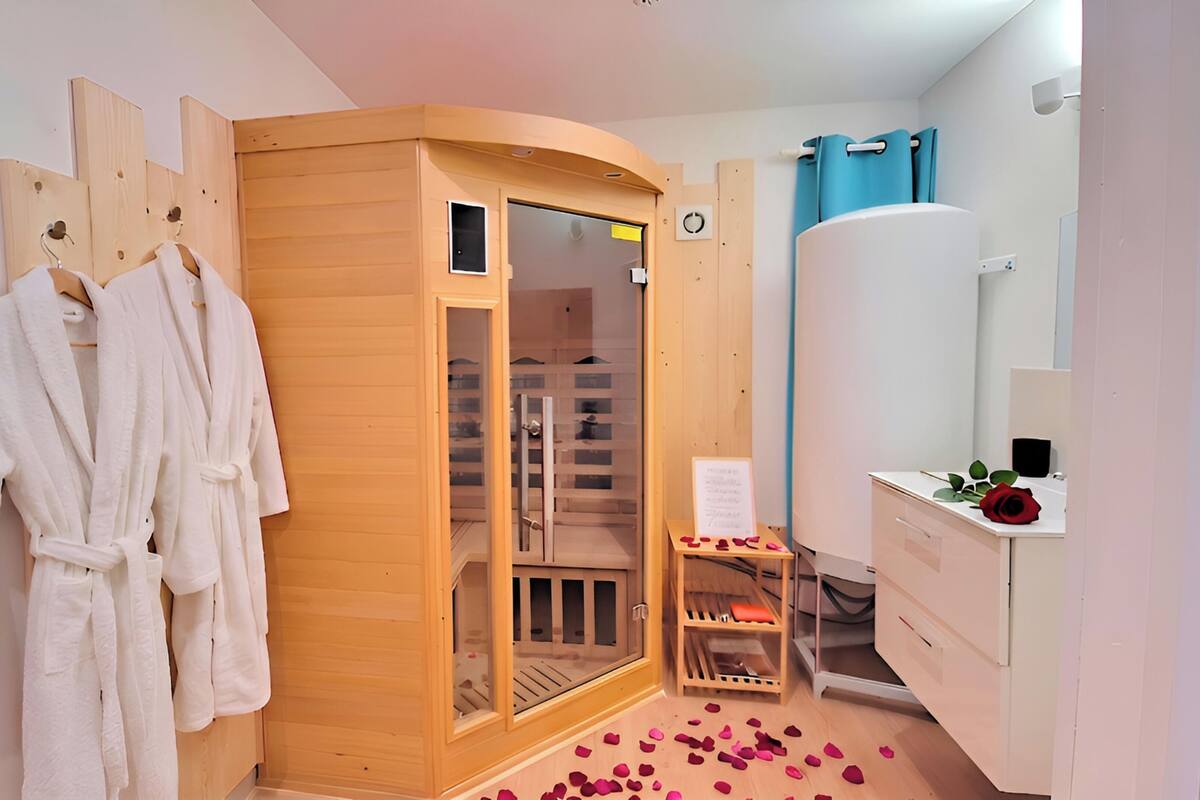 Een sauna met houten wanden, een glazen deur en een klein houten plankje met rozenblaadjes.