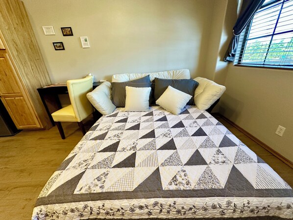 A bedroom with a bed, a chair, a nightstand, and a window. - Year Round Monthly Rental Studio WIFi Desk Wild Mustangs nearby Nat'l For (Overgaard)