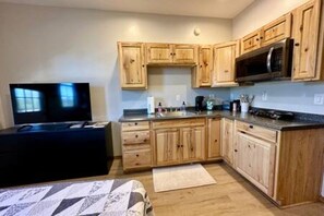 Een kleine keuken met houten kastjes, een magnetron en een televisie.