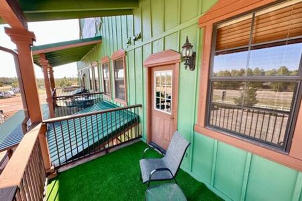 A room with a green artificial turf floor, a wooden bench, and a window with blinds.