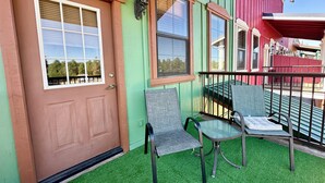 A porch with two chairs and a table, a brown door, and a green wall. - Year Round Monthly Rental Studio WIFi Desk Wild Mustangs nearby Nat'l For (Overgaard)