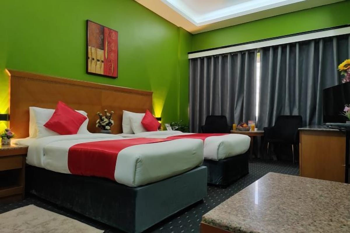 Una habitación de hotel con una cama grande, dos mesitas de noche, un escritorio y una silla.